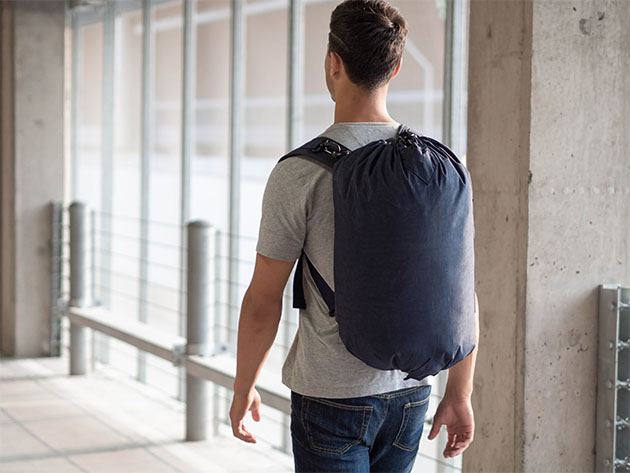 A man walks away from camera wearing a three-in-one travel bag in backpack form.