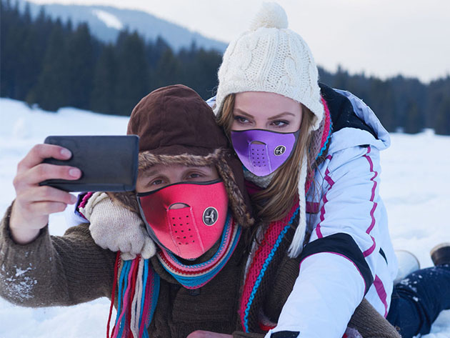People on the ski slopes taking a selfie and wearing face masks.