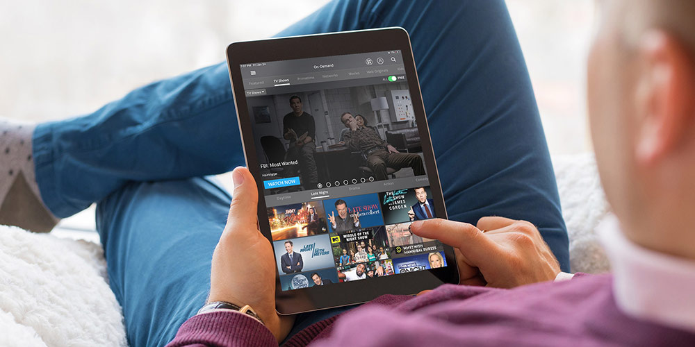 A man holding an iPad looking at a streaming service site