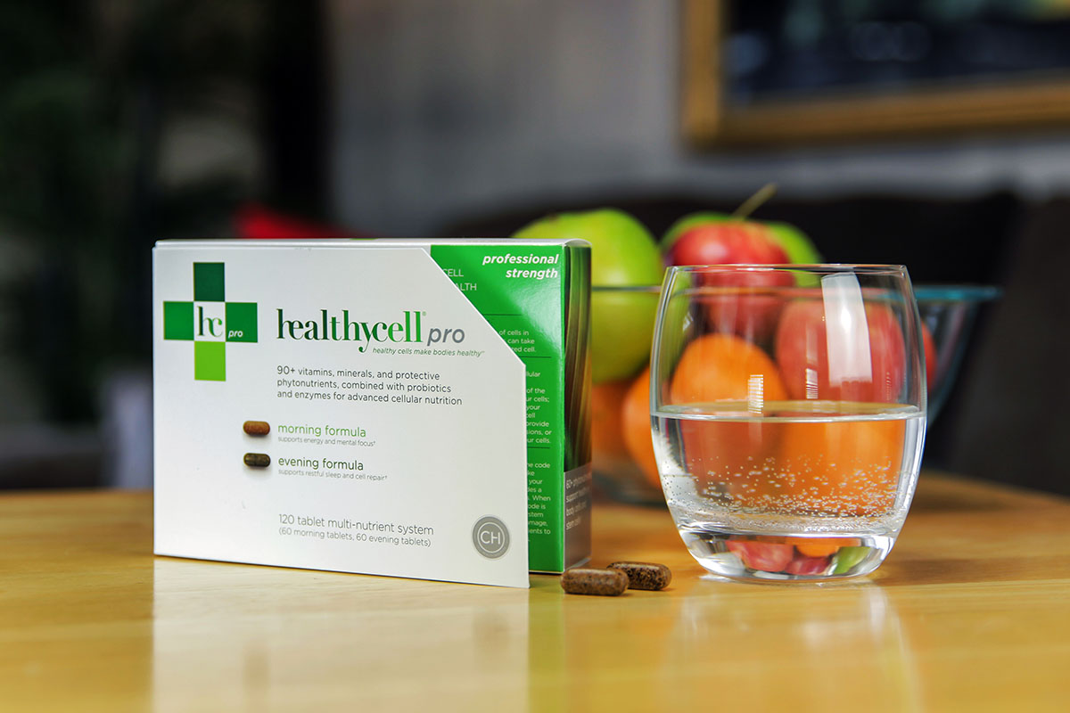 A box of healthycell pro supplements, on a table with a glass of water