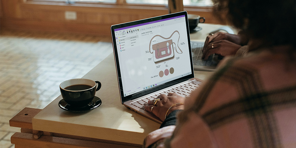 A person typing on a laptop in a cafe 