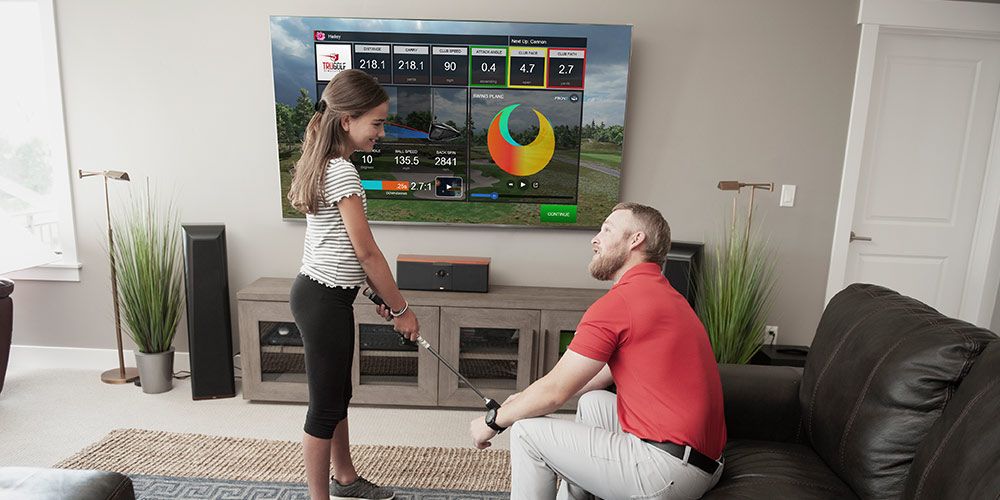 A man and his daughter playing golf on a TV screen in a living room 
